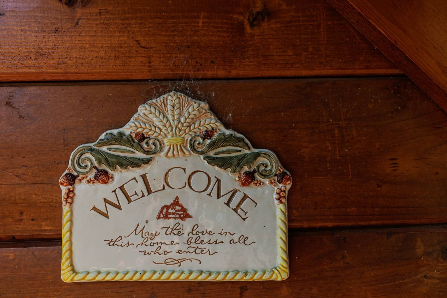 A welcome sign is hanging on a wooden wall