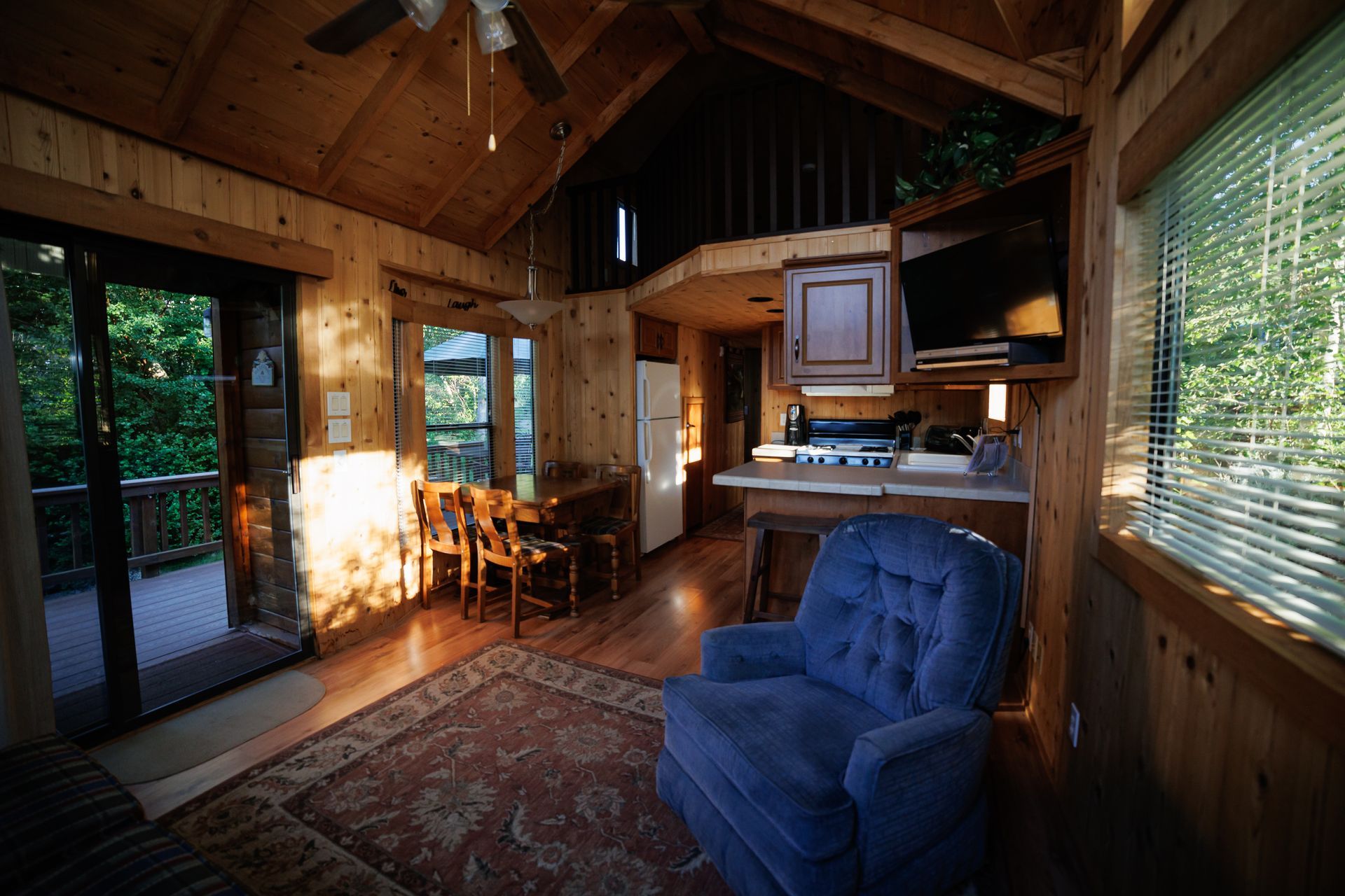 A living room with a blue chair and a ceiling fan