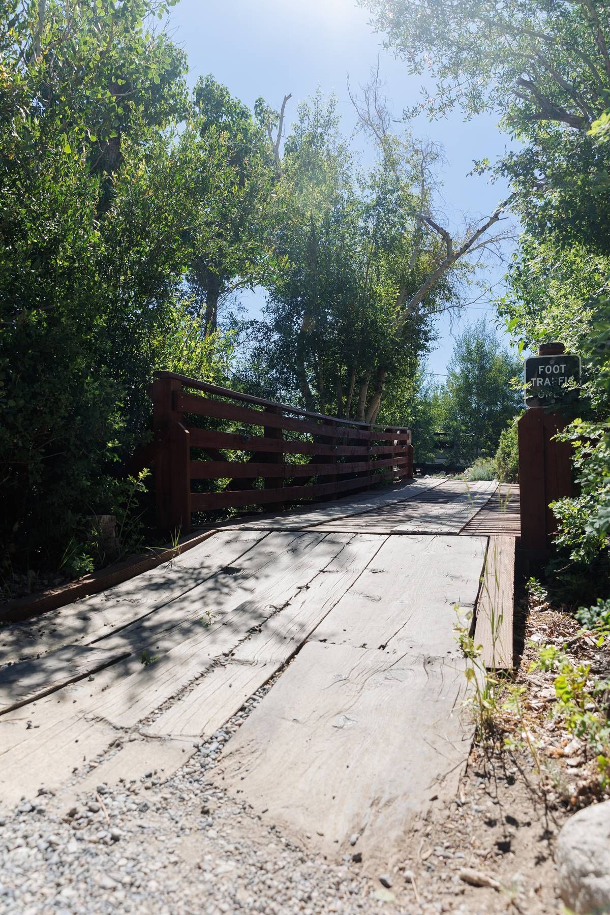 A wooden bridge over a dirt road surrounded by trees