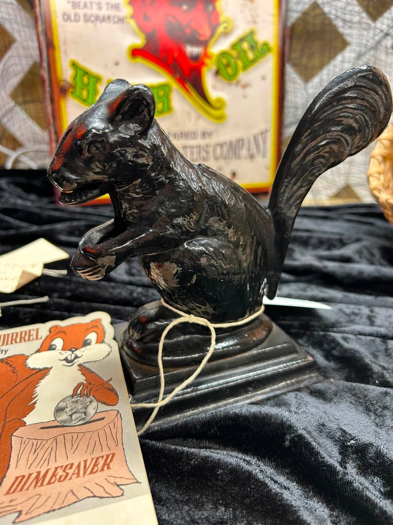 Black squirrel figurine on a black cloth with a small tag and Halloween-themed background