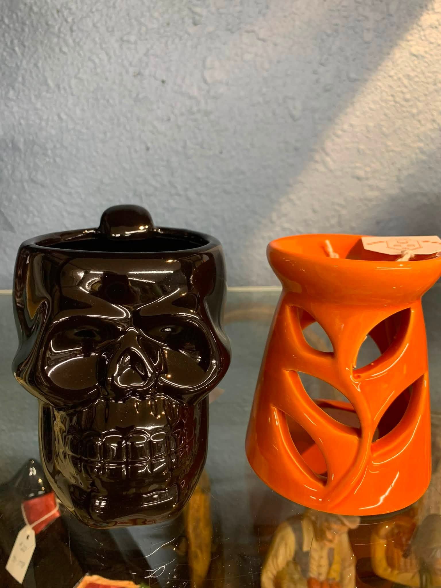 Black skull jar and orange cutout lanterns on a shelf