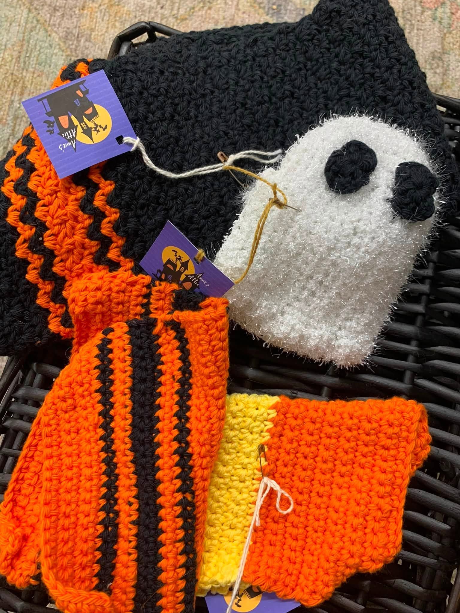 Orange, black, white, and gray crocheted ghost and striped accessories with tags on a dark background