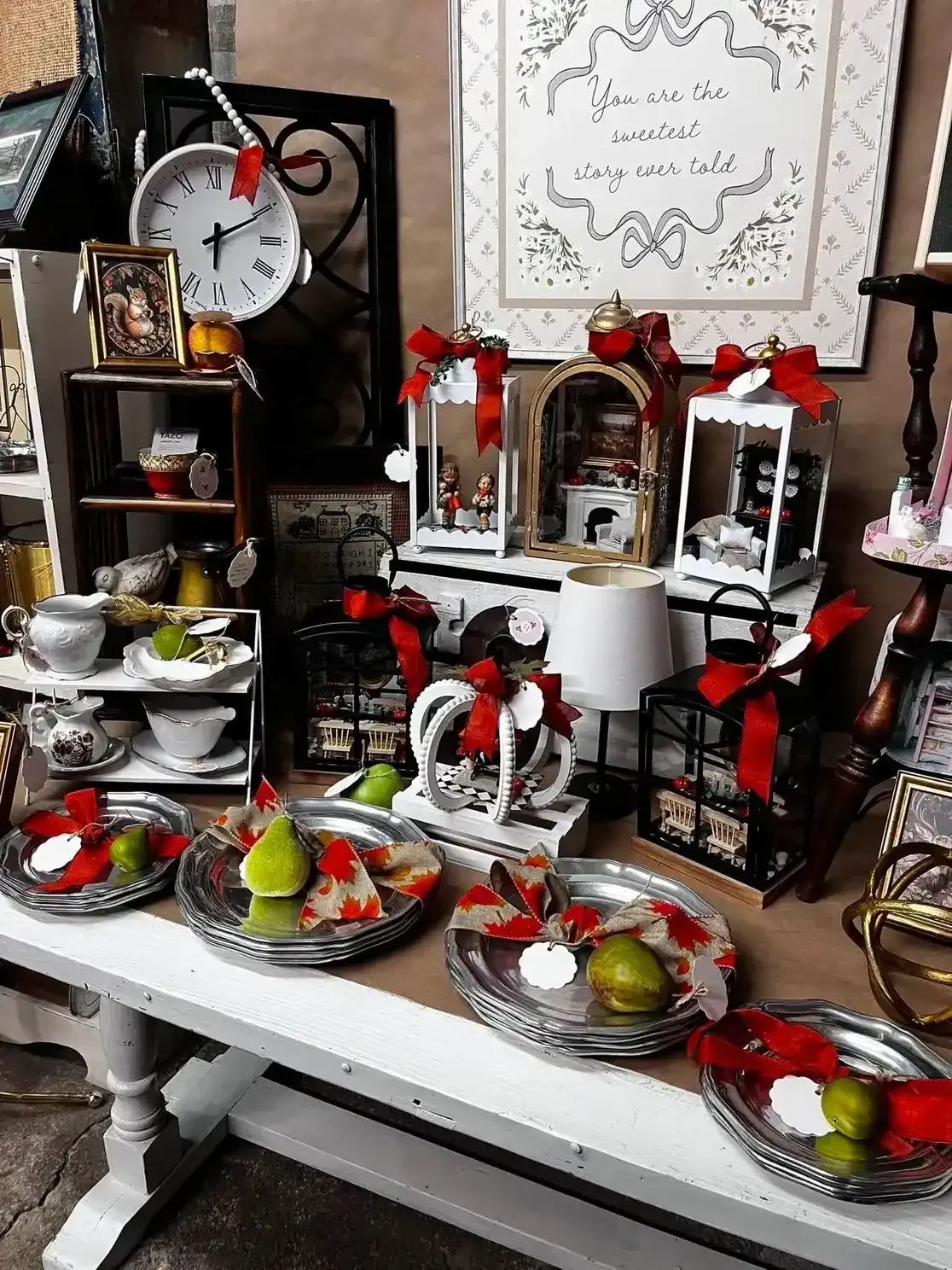 Decorated dessert table with pastries, fruit, candles, and red floral accents in a festive setting