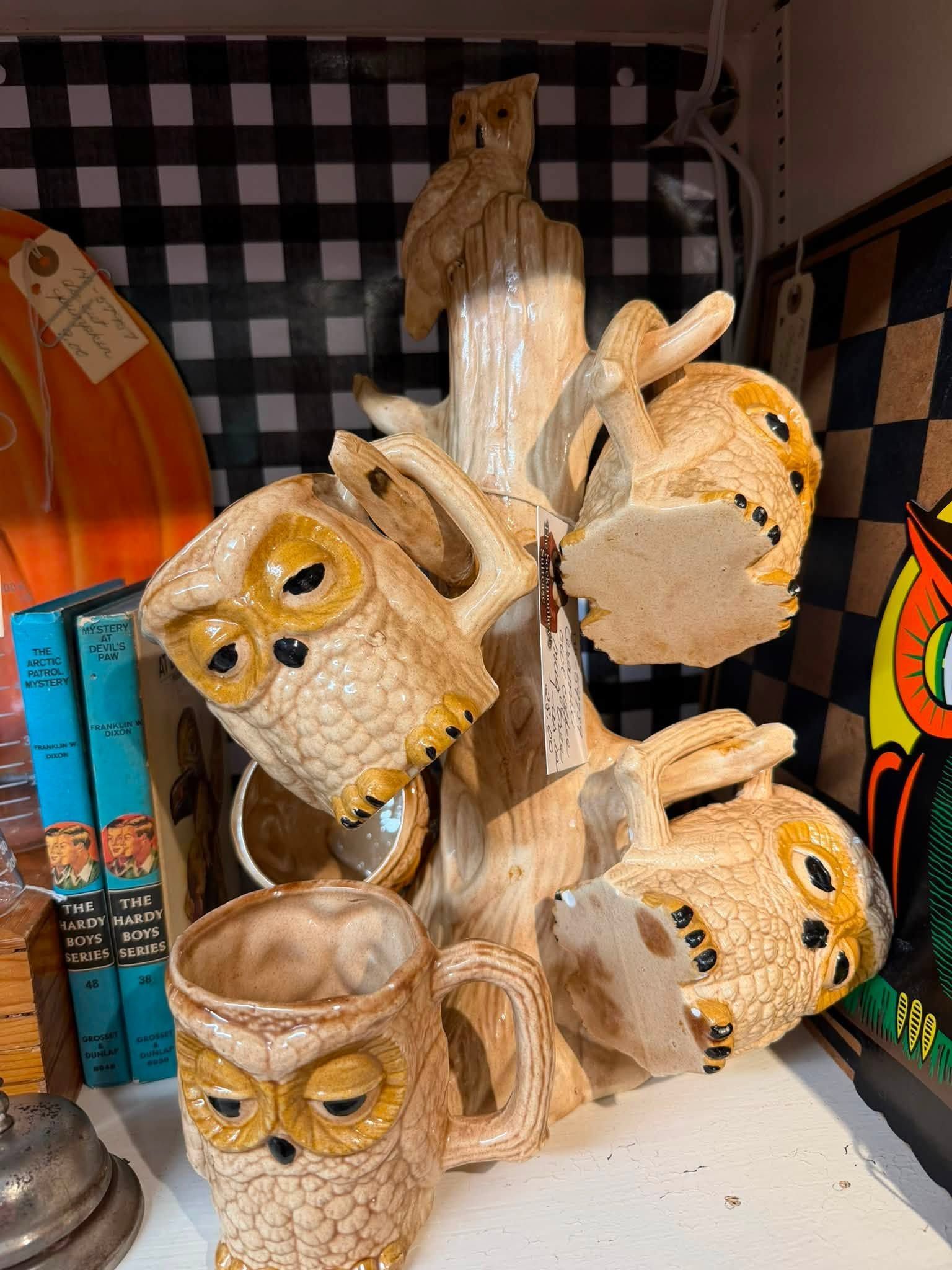 Carved owl figurines arranged on a display shelf with a checkered backdrop.