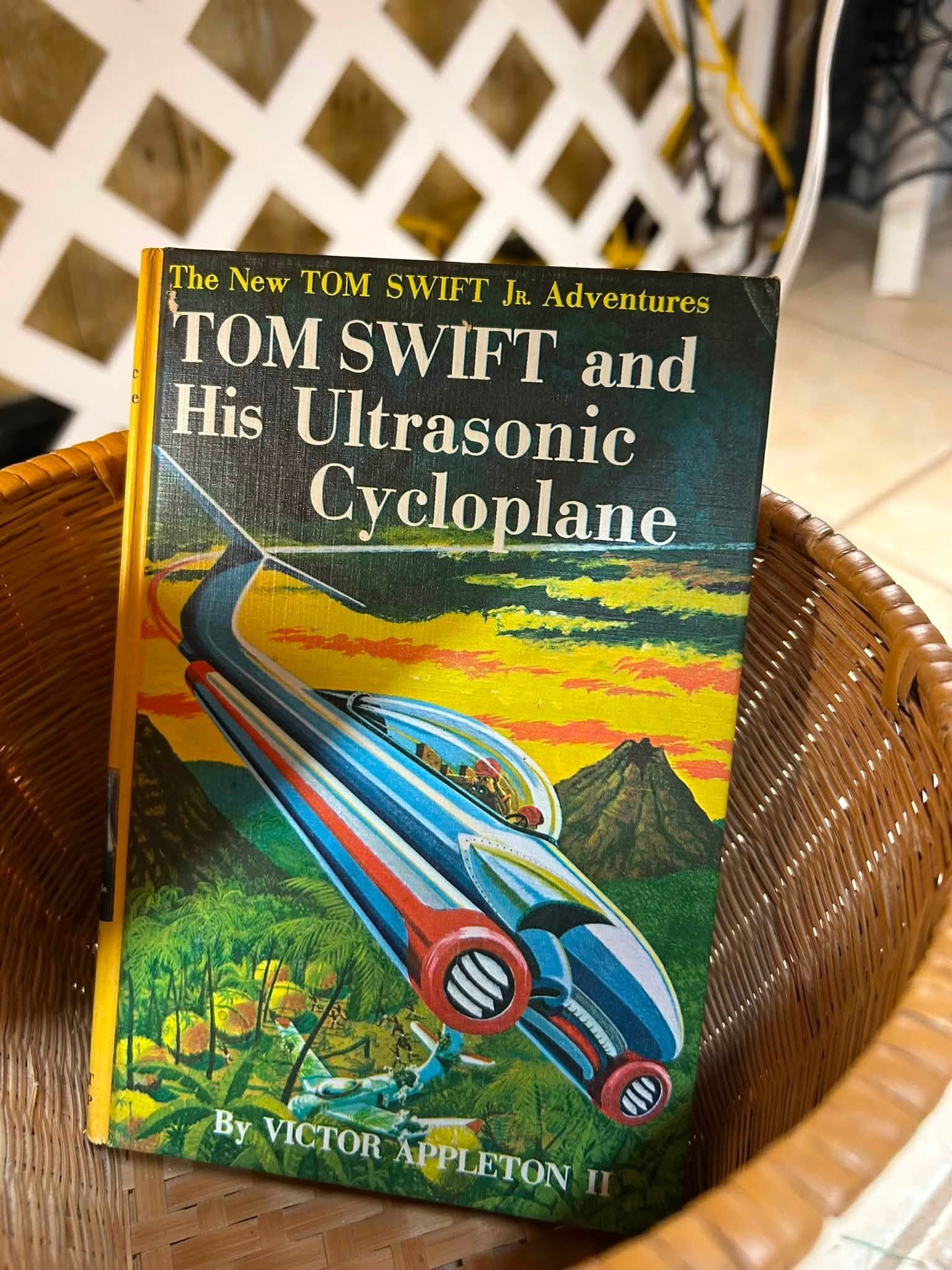 Tom Swift and His Ultrasonic Cycloplane book cover in a basket on a patterned rug.