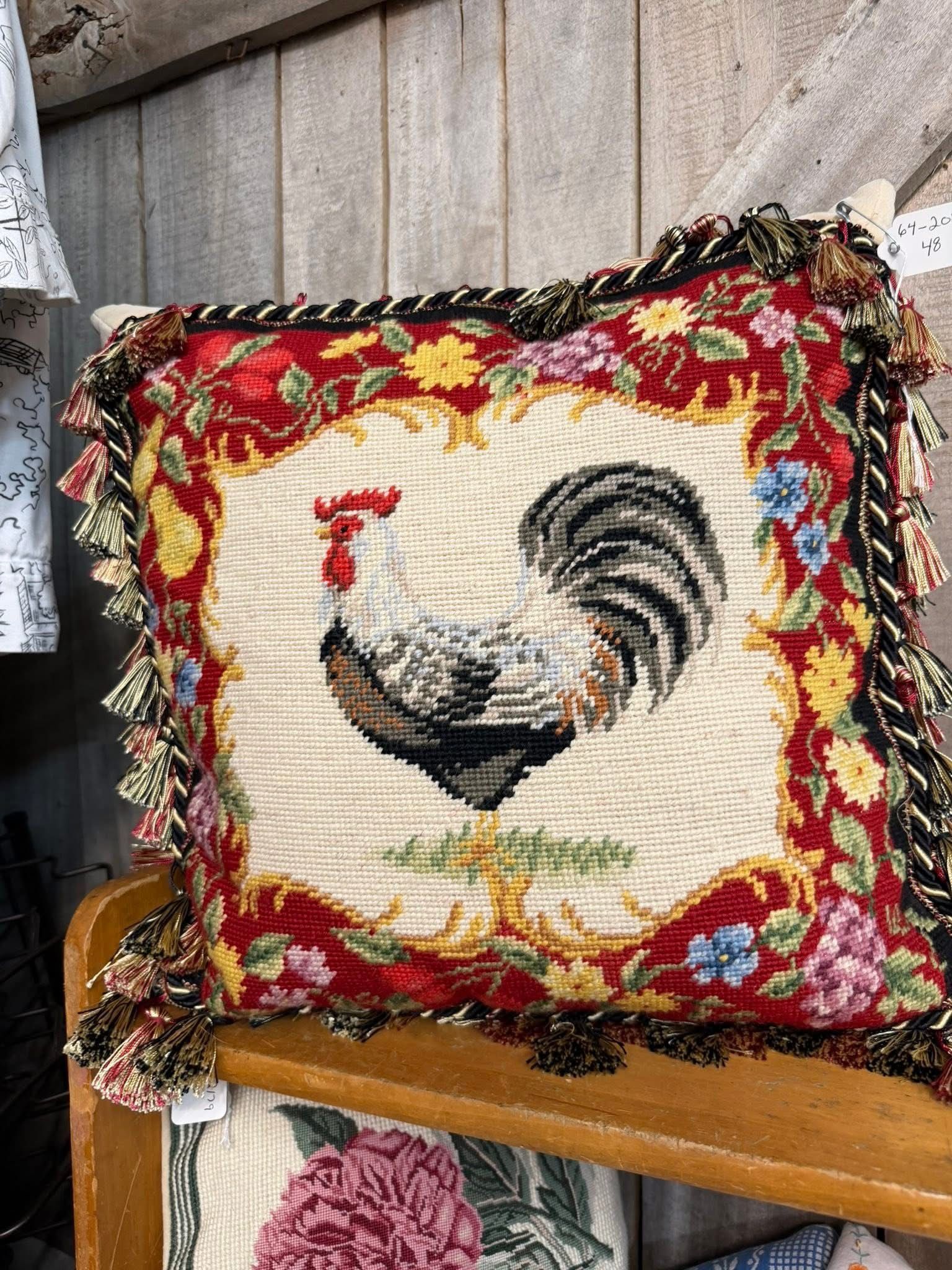 Rooster-themed decorative pillow with red and black trim on a wooden surface
