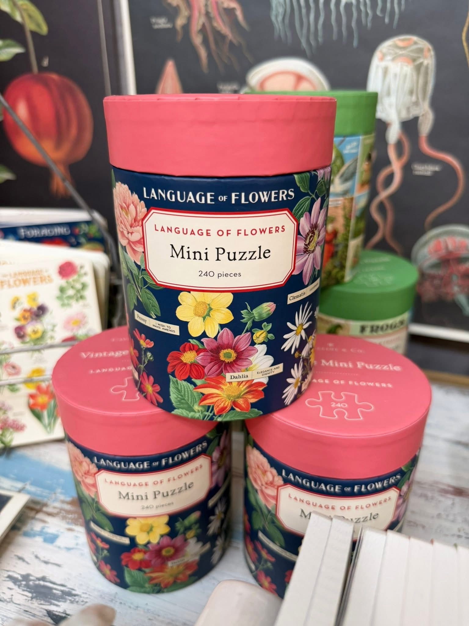 Stacked floral tins of L’Occitane Mini Petals candles with pink lids on a store display