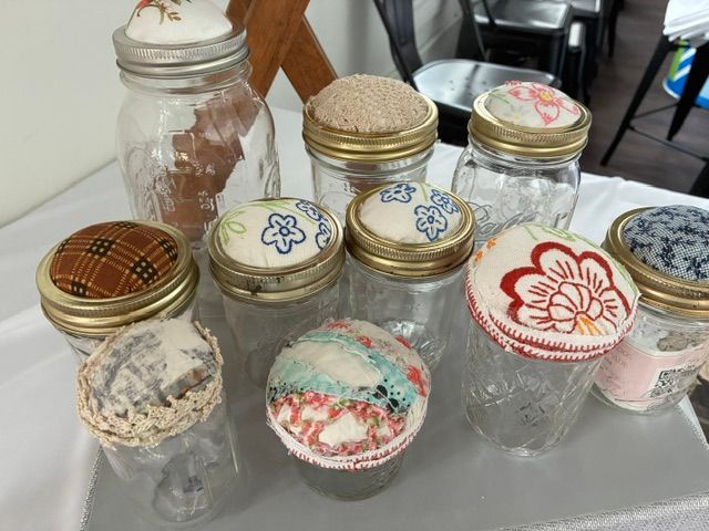 Assorted decorated glass jars and jars with fabric lids arranged on a table