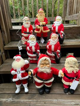 Collection of Santa Claus figurines in red and white outfits displayed on outdoor steps