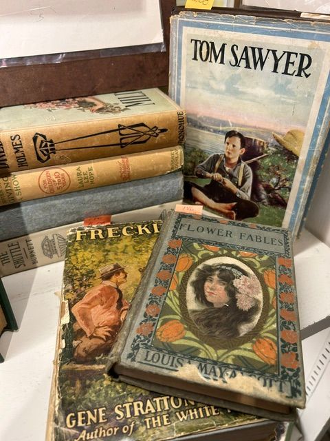 Stack of vintage books, including Tom Sawyer and other illustrated hardcover novels.