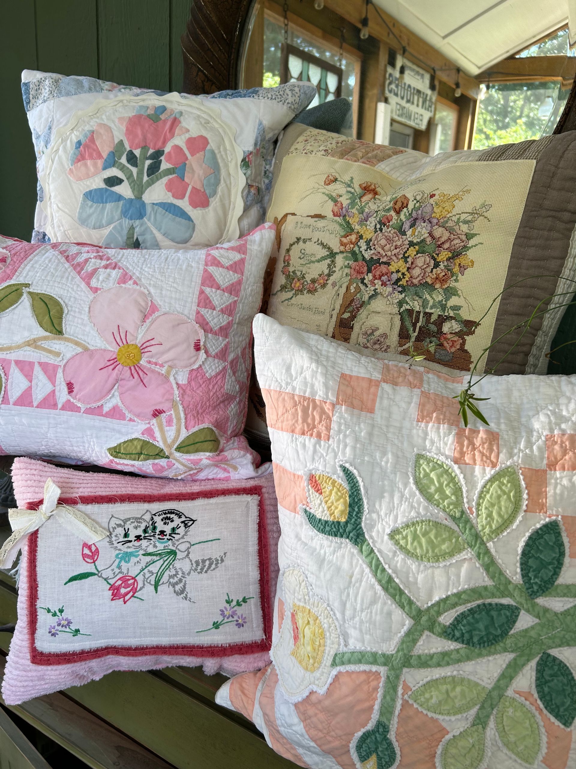 Decorative floral quilts and pillows stacked on a couch in a cozy room.