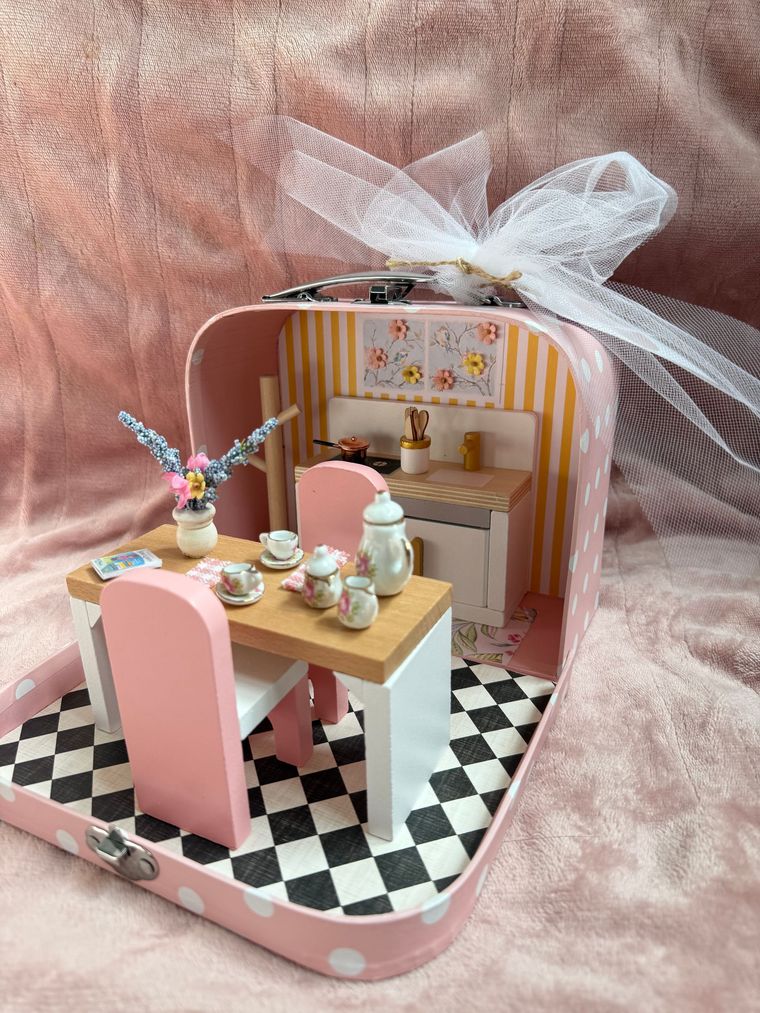 Miniature pink dollhouse dining room with table, chairs, and tiny decor inside a gift box