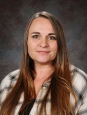 The woman is wearing a denim jacket and smiling for the camera.