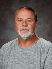 A man with a beard and a white shirt is smiling for a picture.