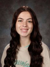 A young woman is smiling for a picture in front of a green background.