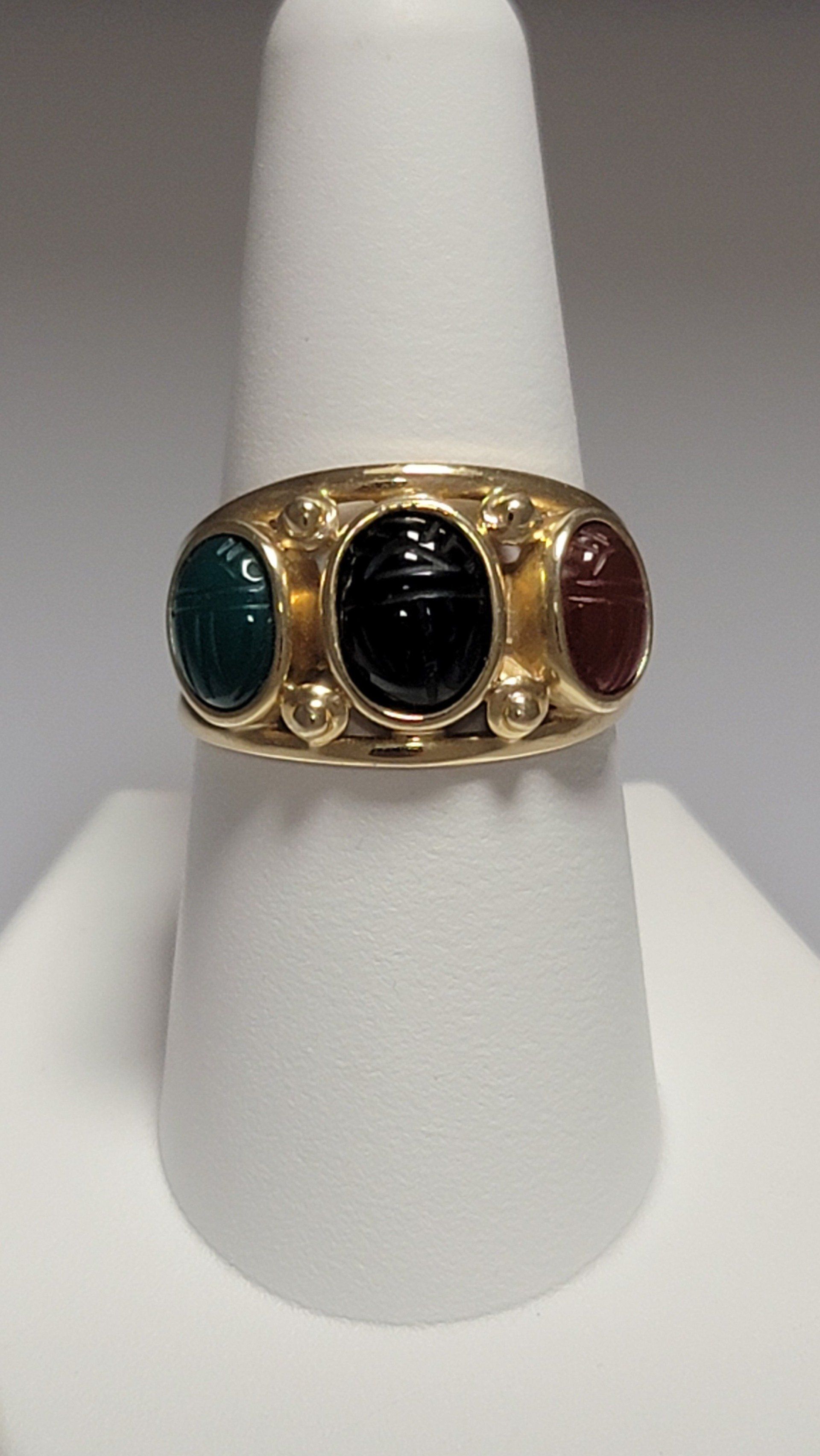 Gold ring with three oval scarab stones: green, black, and red.