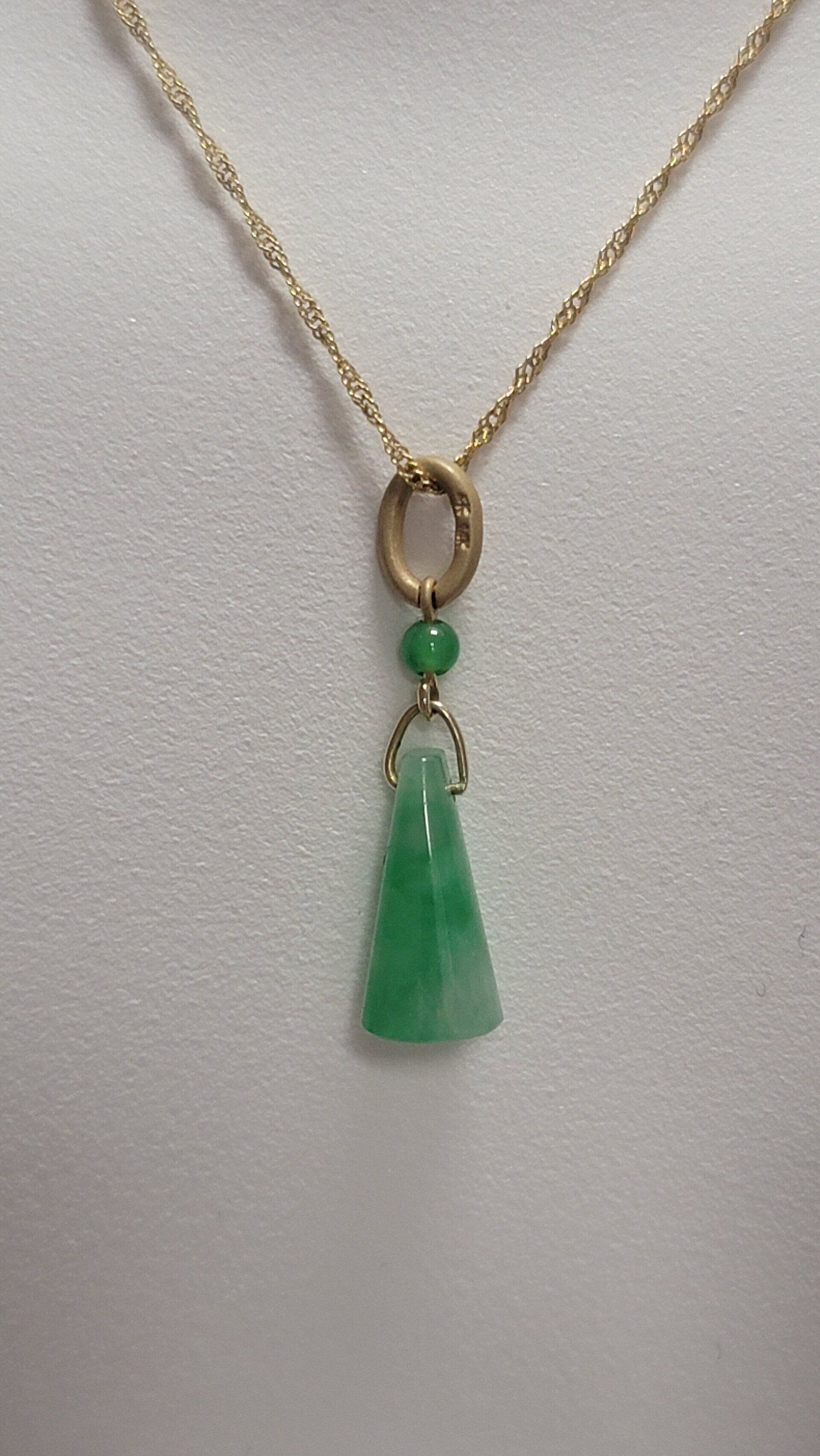 Gold necklace with a green jade pendant, displayed against a white background.
