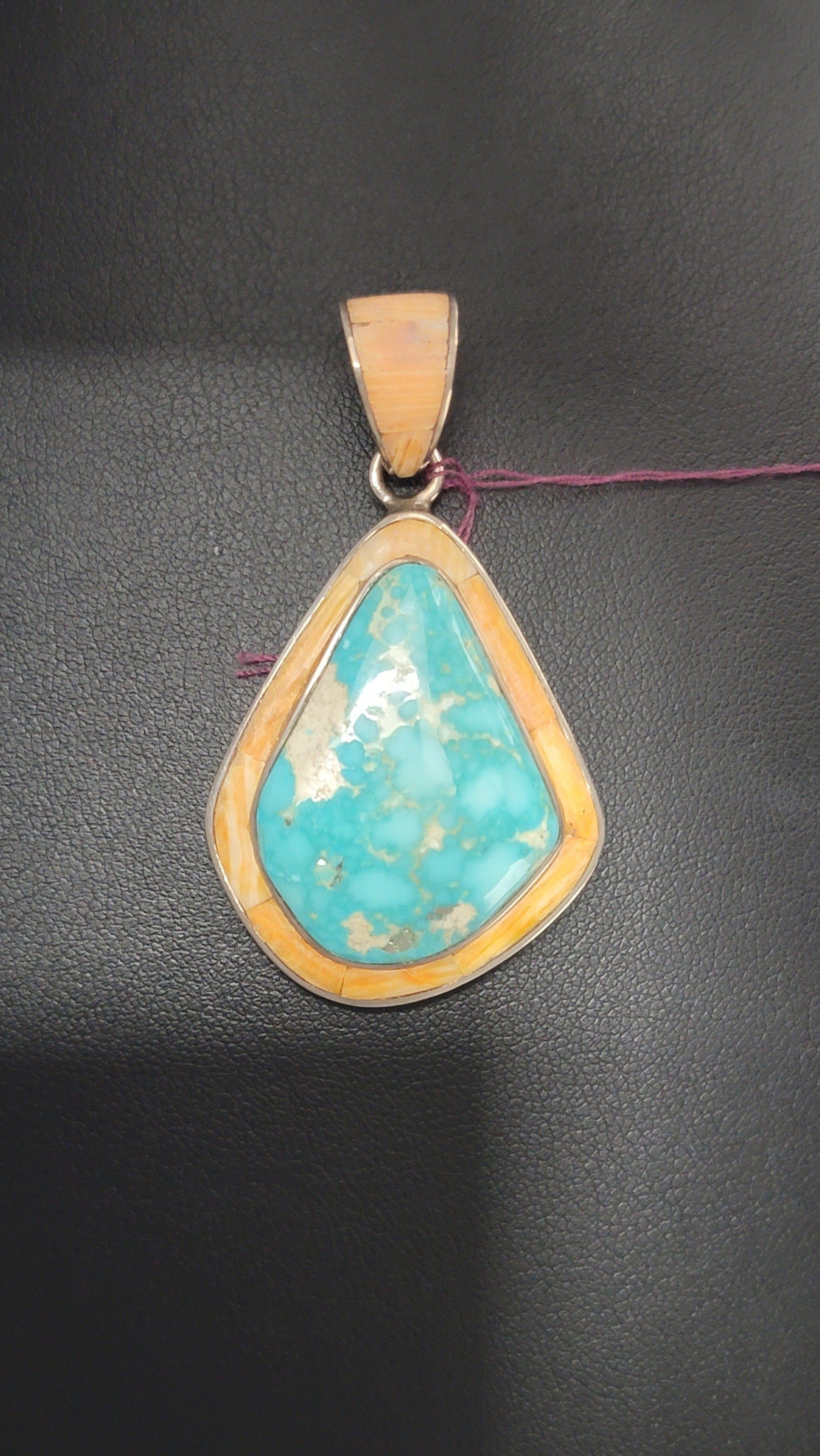 Teardrop-shaped turquoise pendant with gold trim.