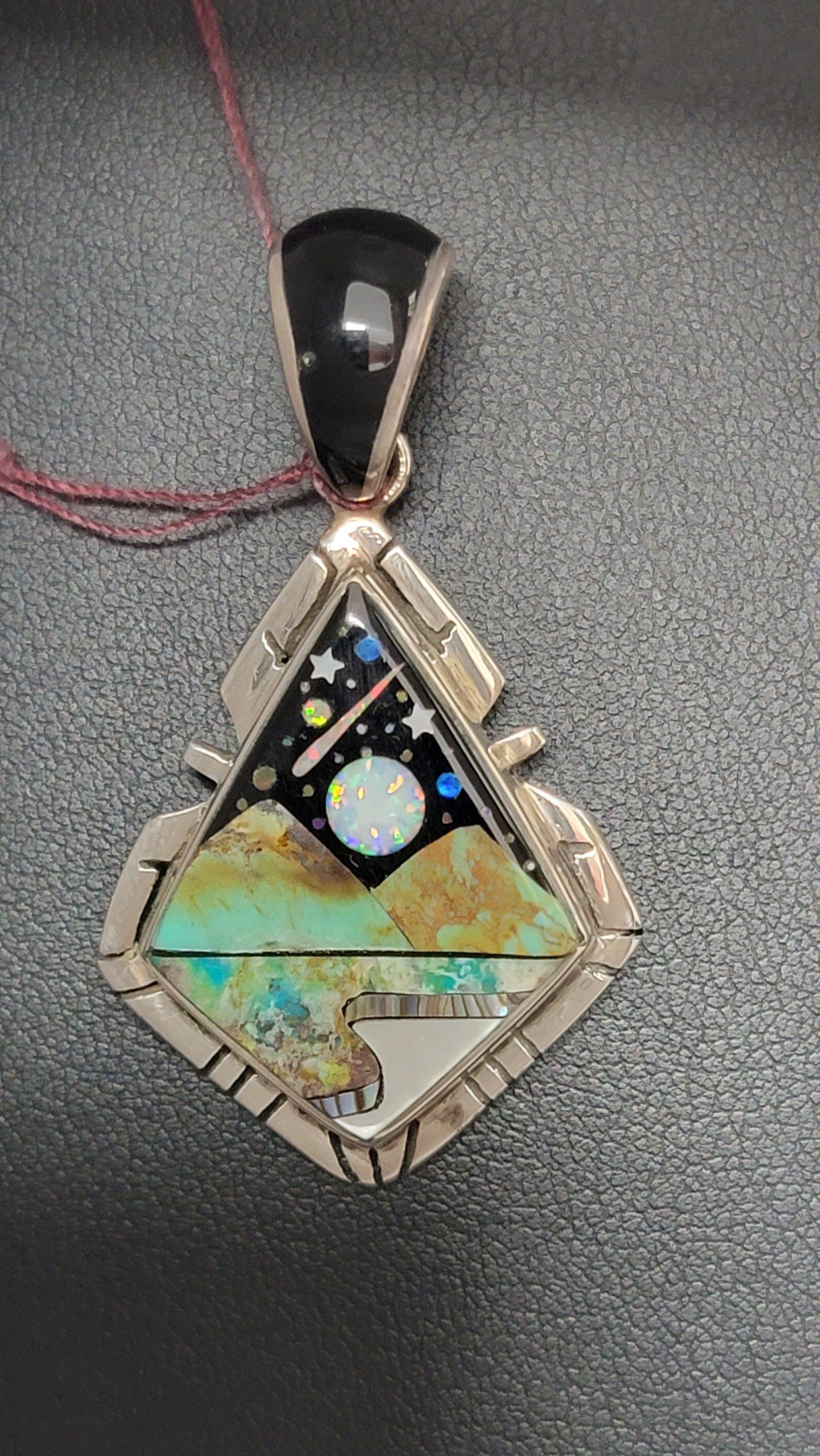 Triangular pendant with a night sky and desert landscape inlay, silver setting, and black onyx top.