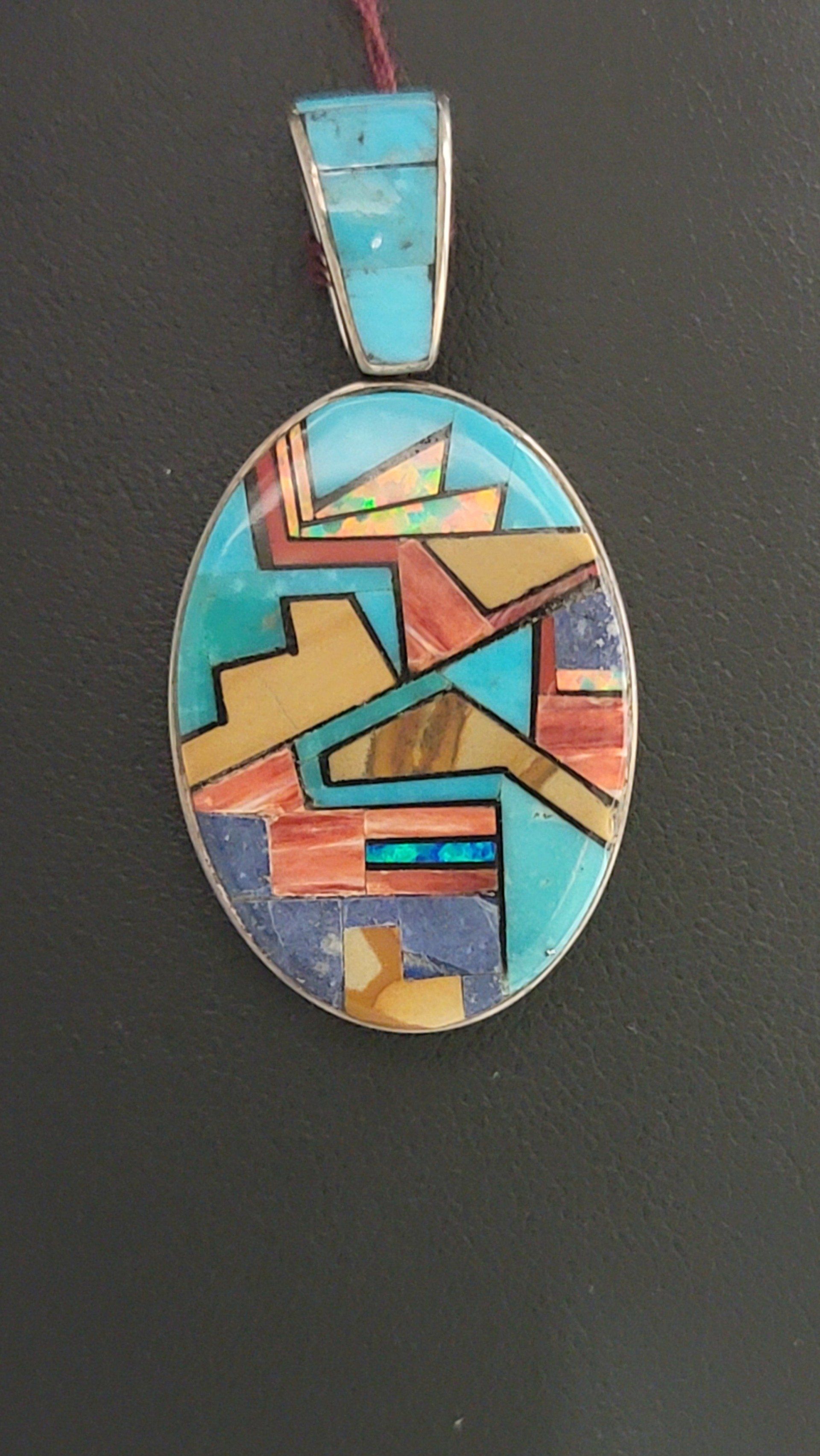 Oval turquoise, silver, and gemstone inlay pendant.