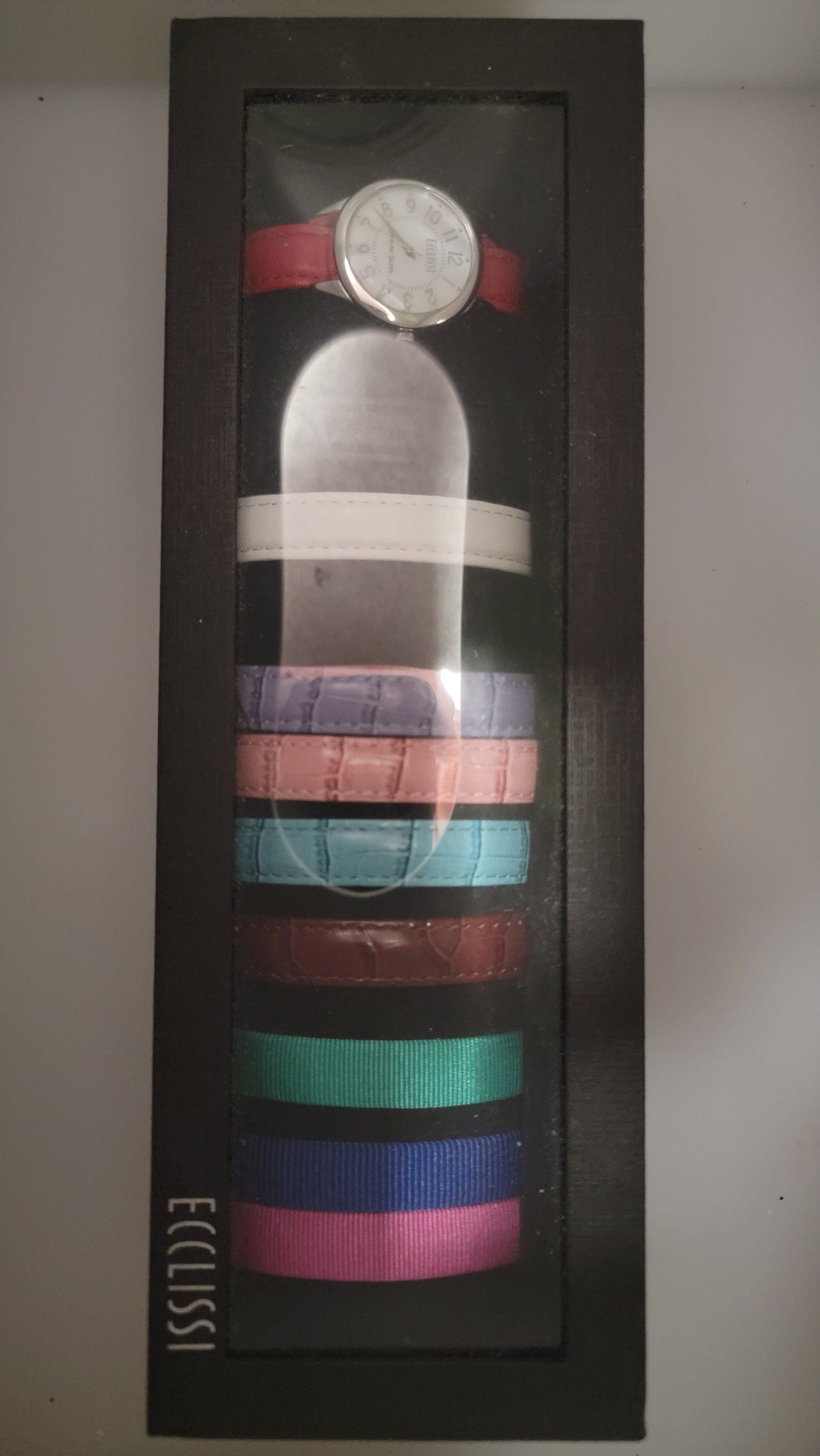 Watch and interchangeable bands displayed in a dark frame; watch has red band.