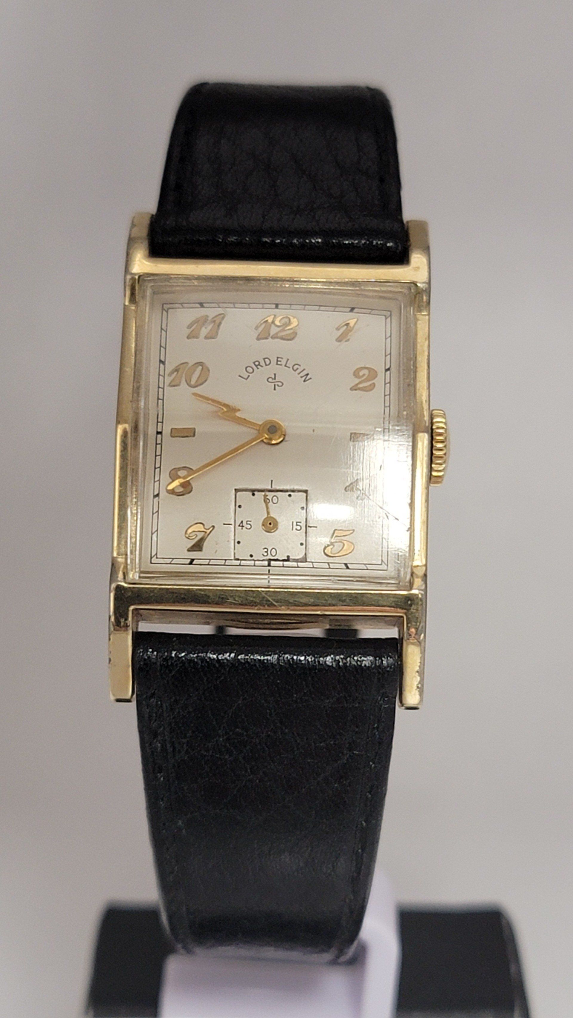 Gold rectangular wristwatch with black leather strap.
