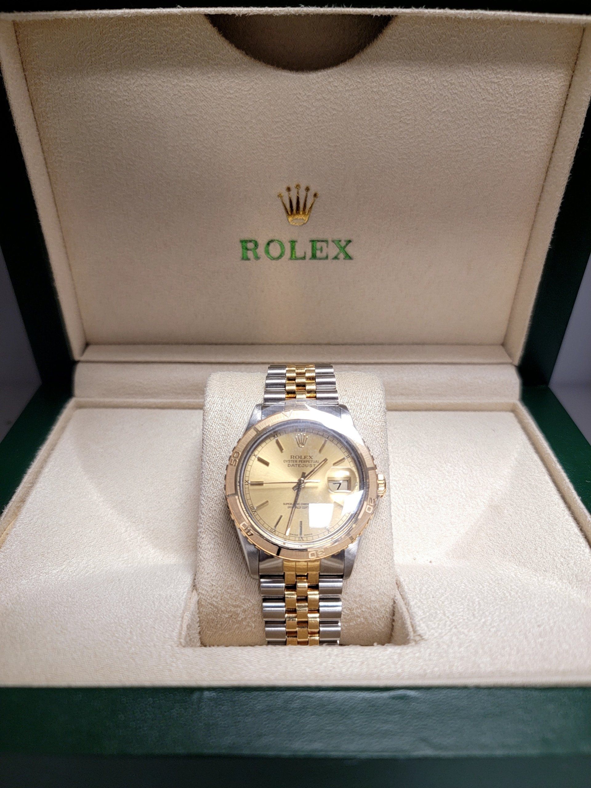 Rolex watch in a green and beige box, gold and silver band and bezel, gold face.