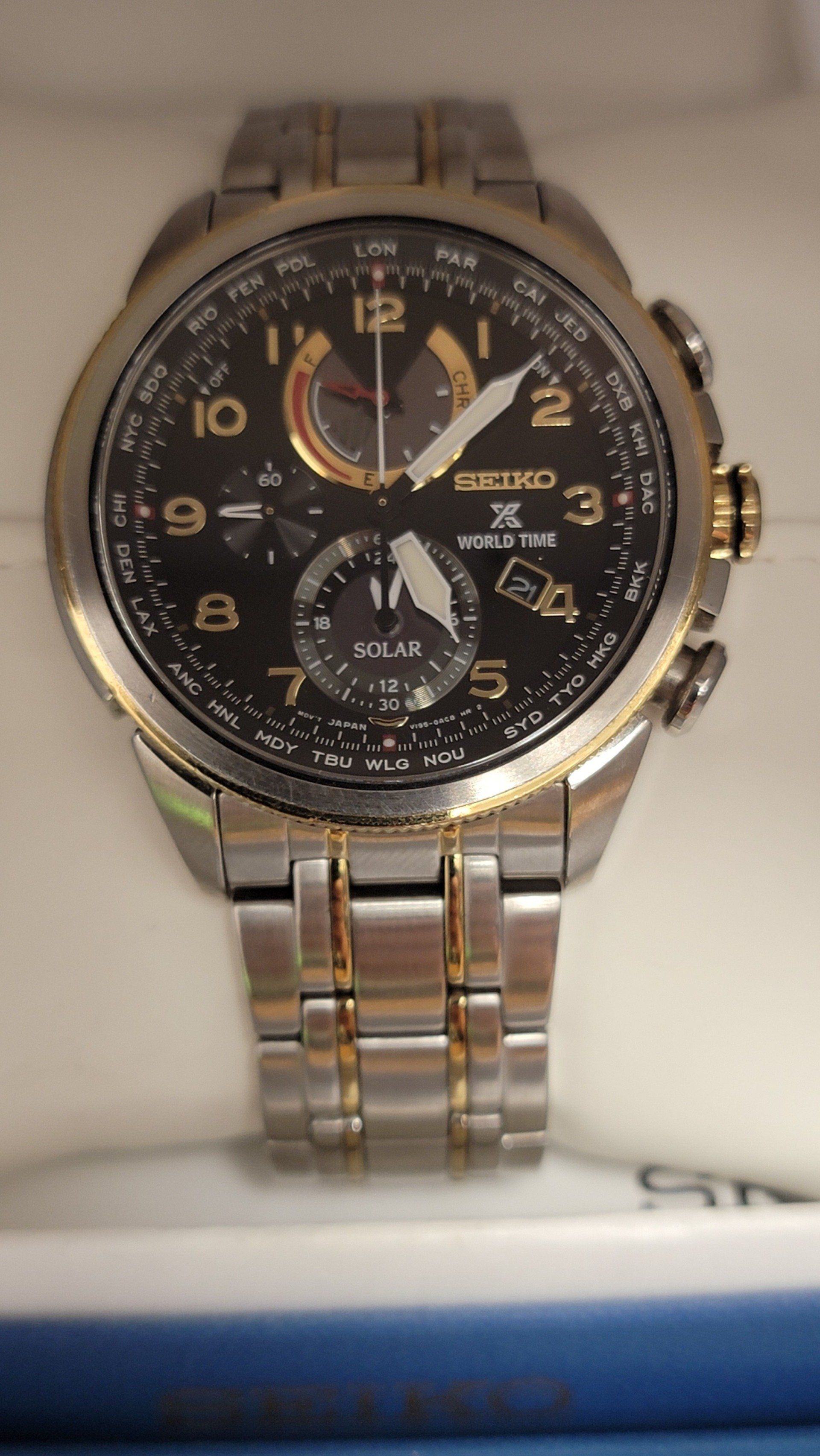 Silver and gold Seiko wristwatch with a black face and date display.