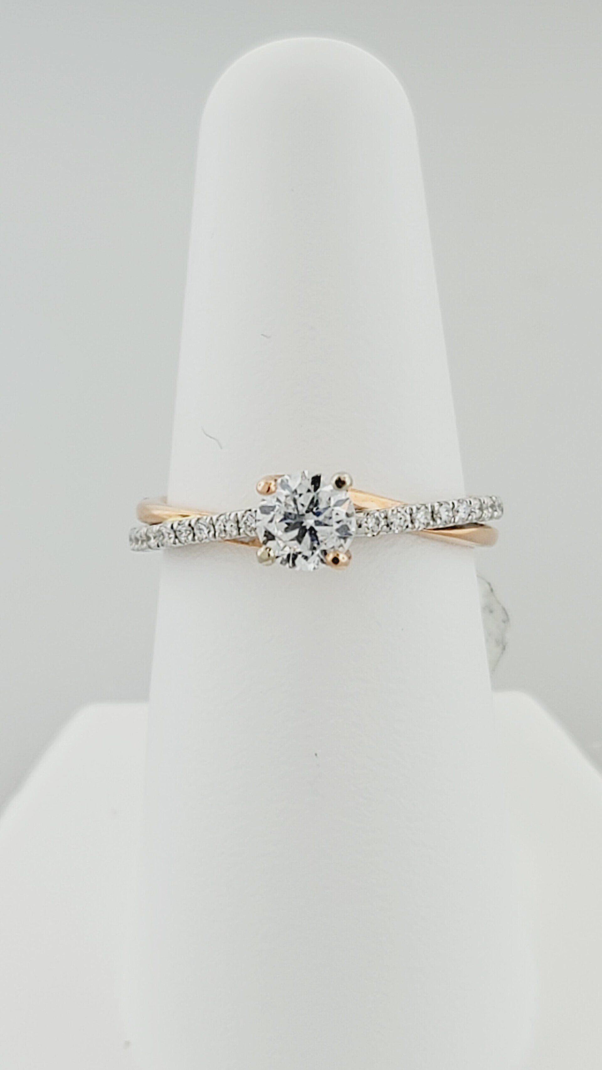 Diamond engagement ring on a white display finger; rose gold band with small diamonds.