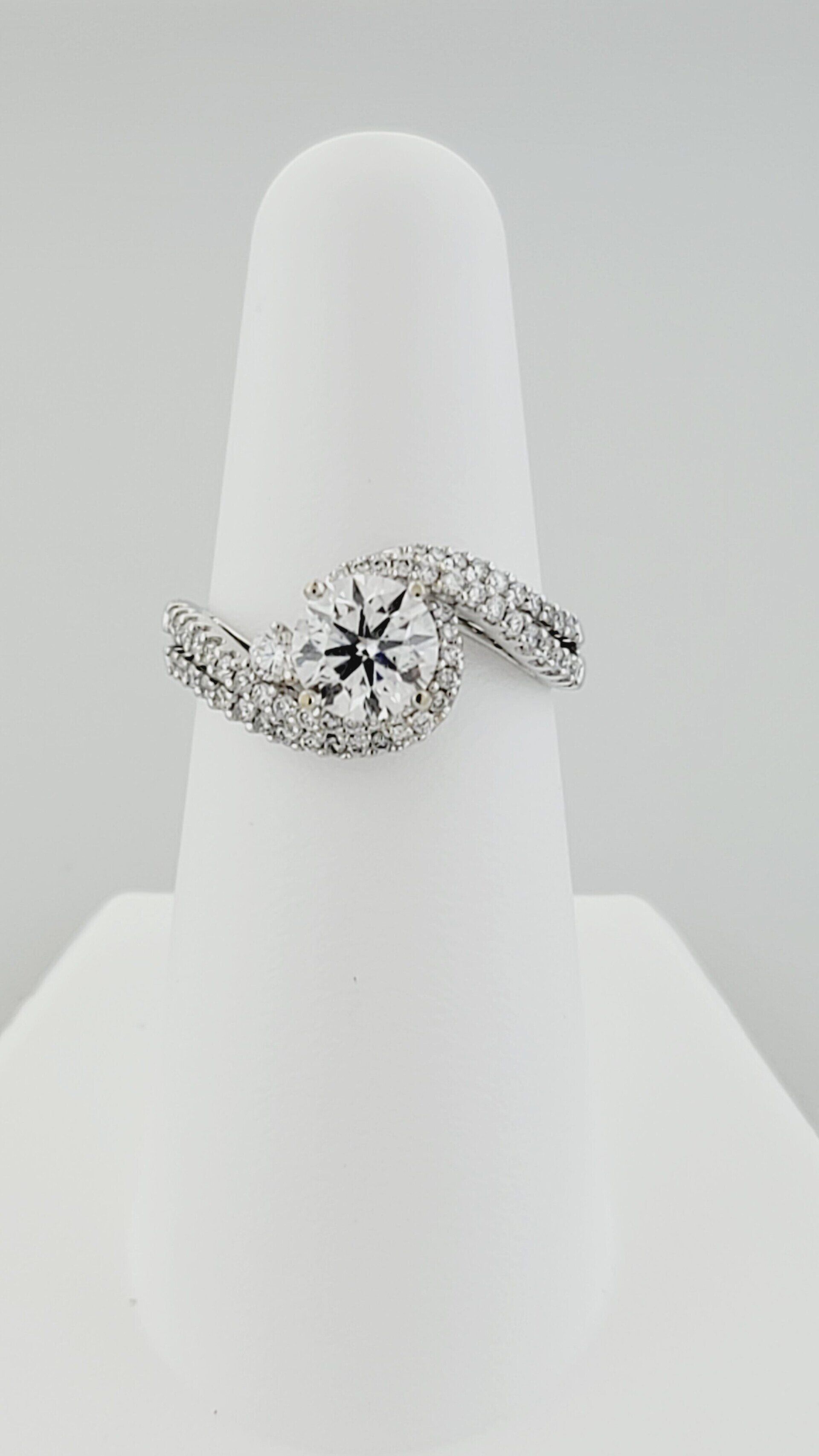 Diamond engagement ring on a white display stand.