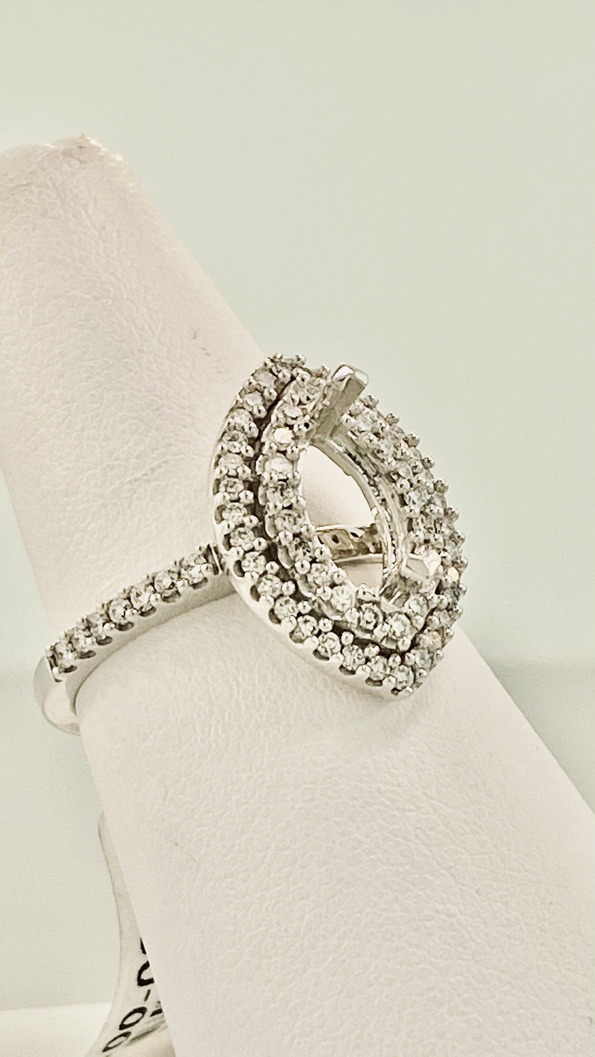 Diamond ring with an oval-shaped, double-tiered cluster of stones, set on a white finger display.