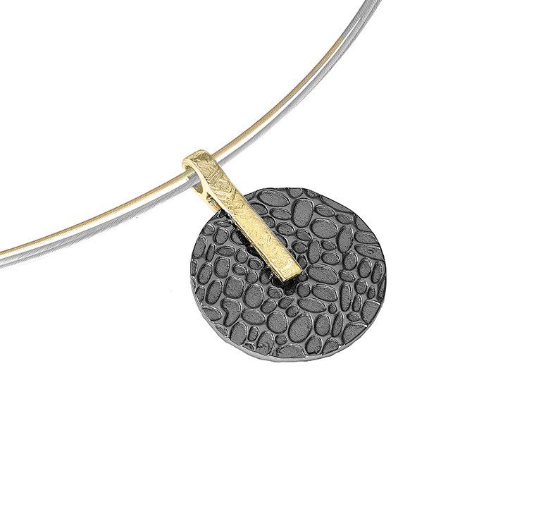 Silver necklace with a gold bar connecting a textured, dark gray circular pendant.