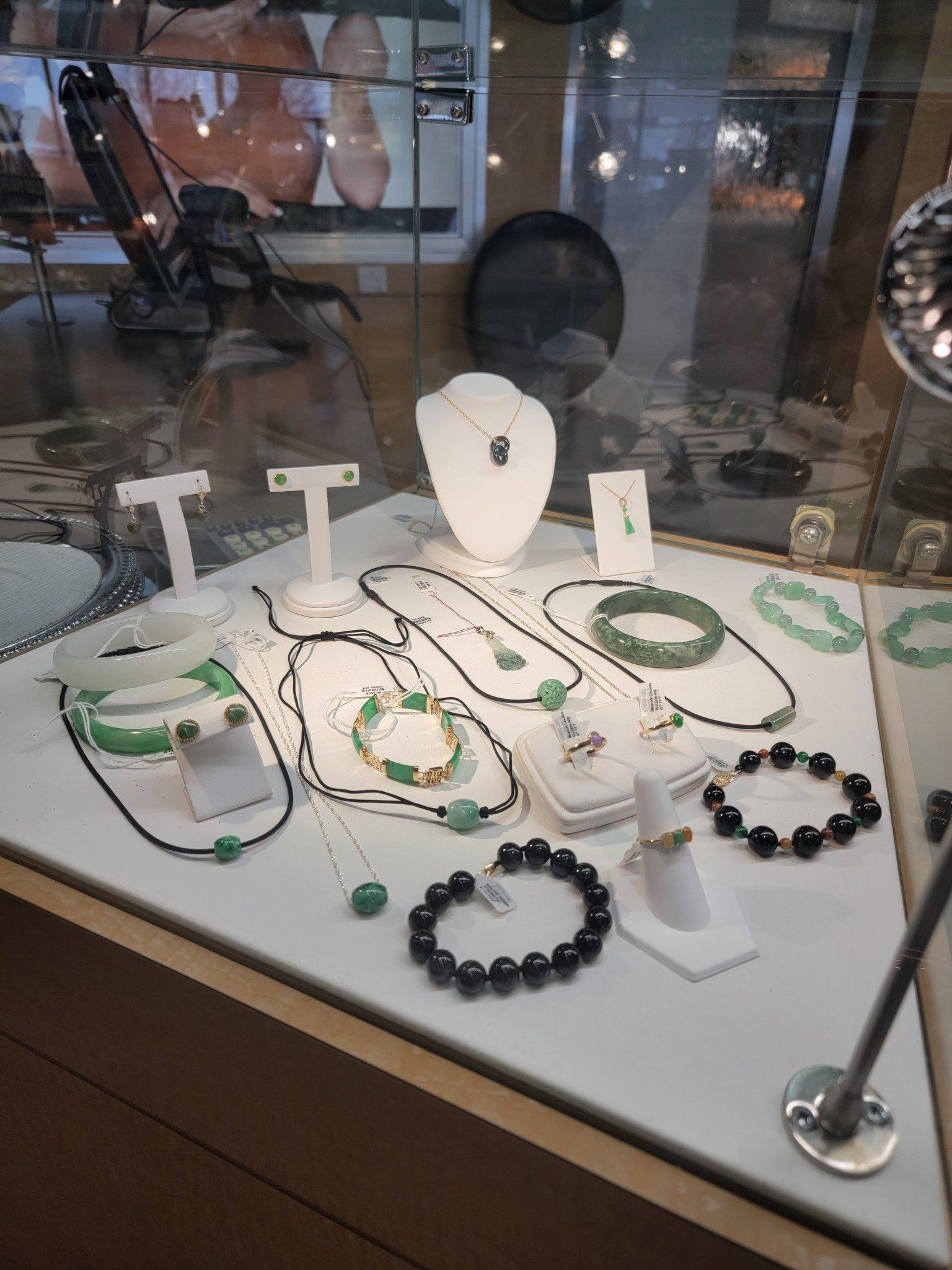 Jewelry display case with necklaces, bracelets, and earrings in shades of green and black.