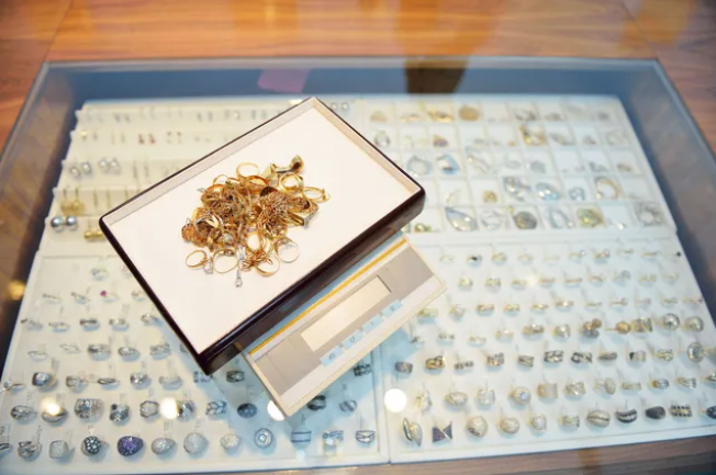 Jewelry display case with a box of gold-toned jewelry and a box on top.