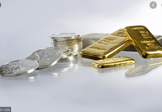 Silver coins and bars alongside gold bars on a reflective surface.