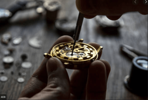 A person using a screwdriver to assemble a golden watch mechanism.