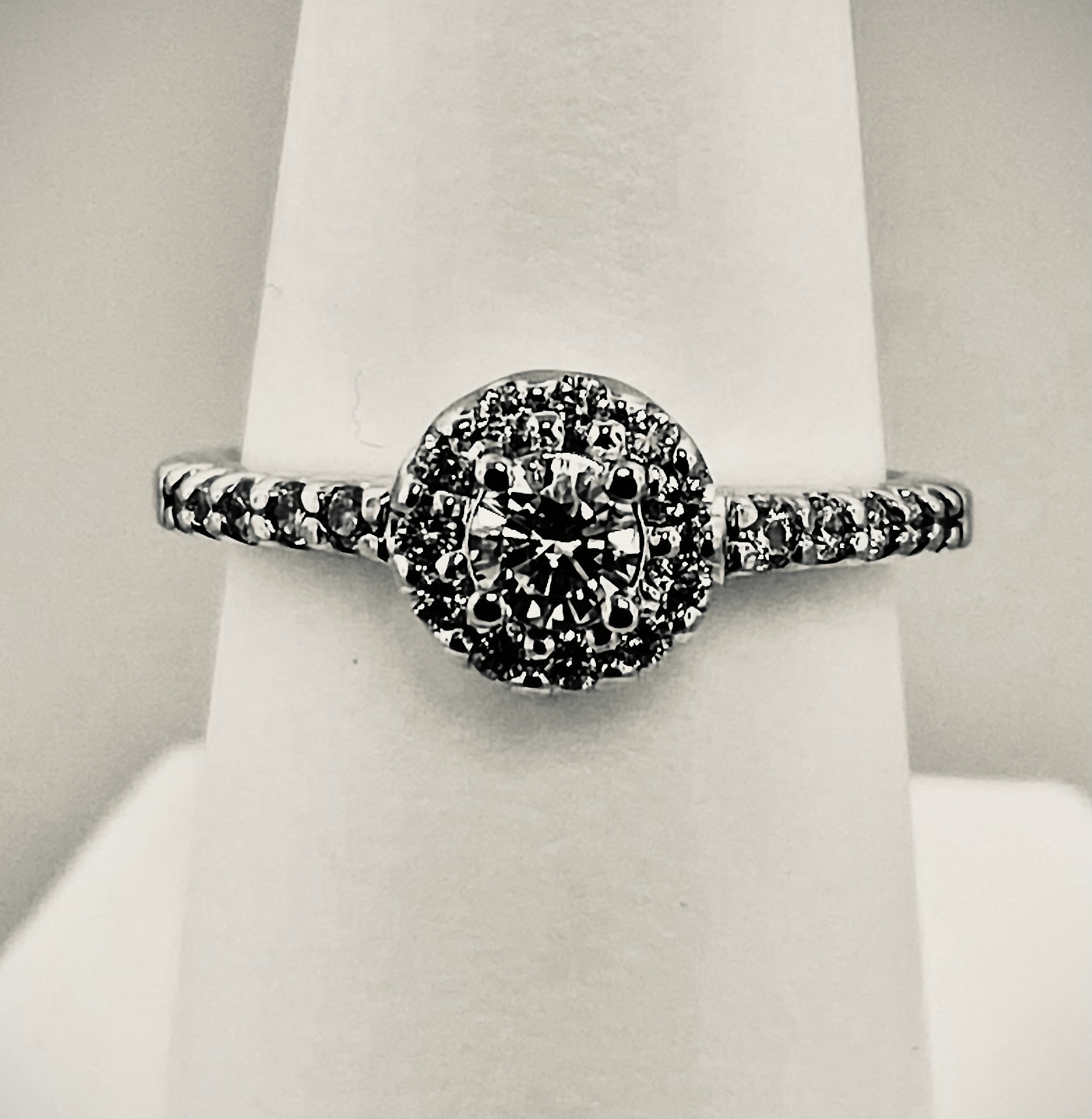 Silver ring with a round cluster of small diamonds at the center and stones along the band.