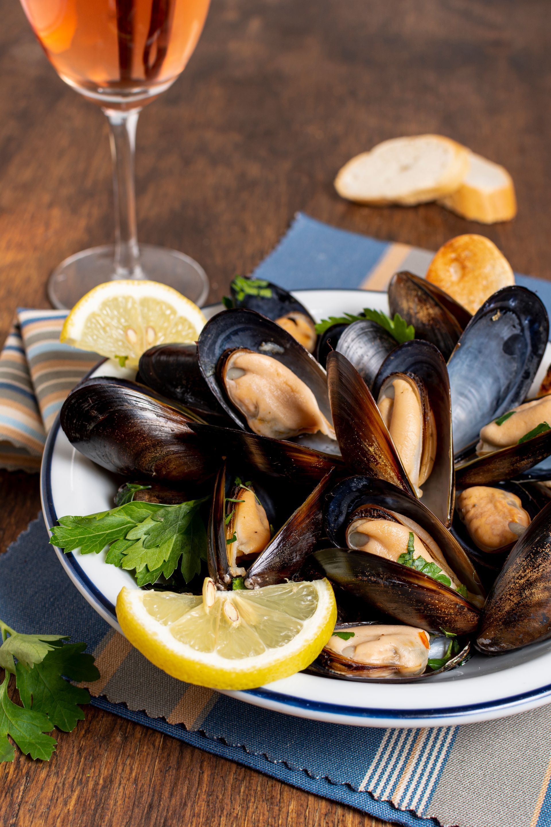 Piatto di cozze al vapore con limone e prezzemolo, servito con vino e pane.