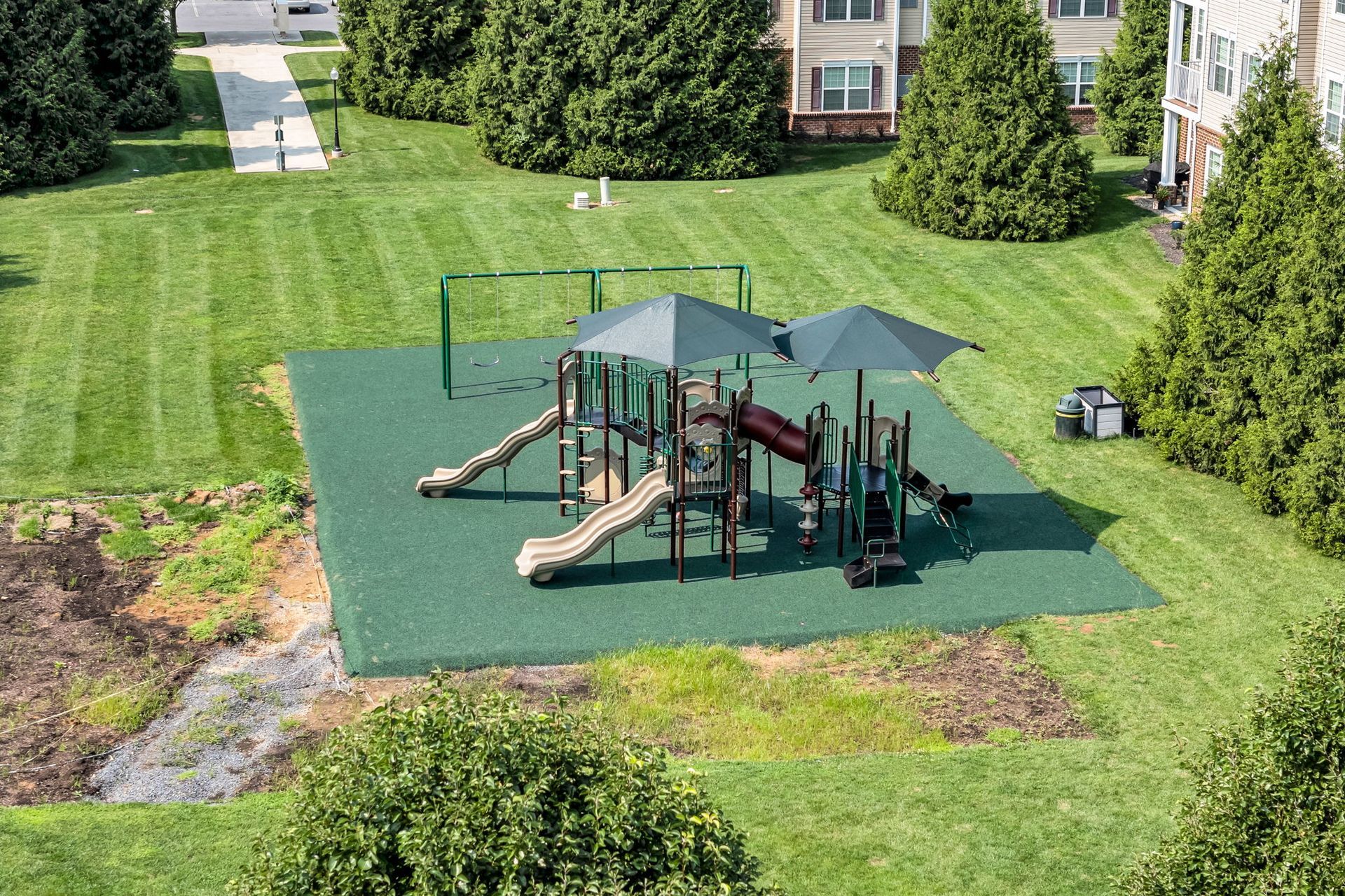 Apartment playground with slides and climbing structures on a green lawn