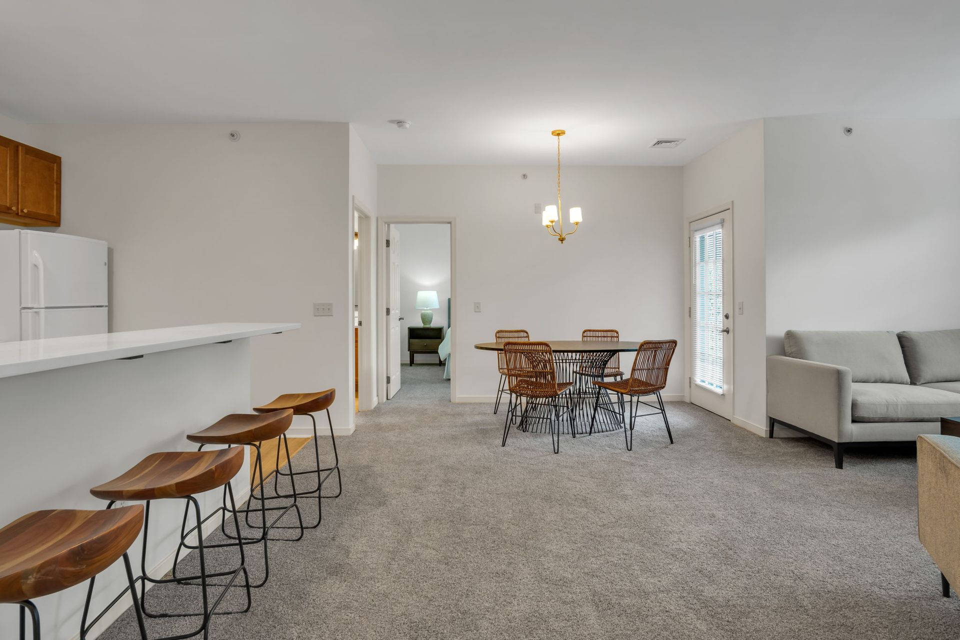 Open kitchen and dining area with bar stools, table, gray sofa, and carpeted floor
