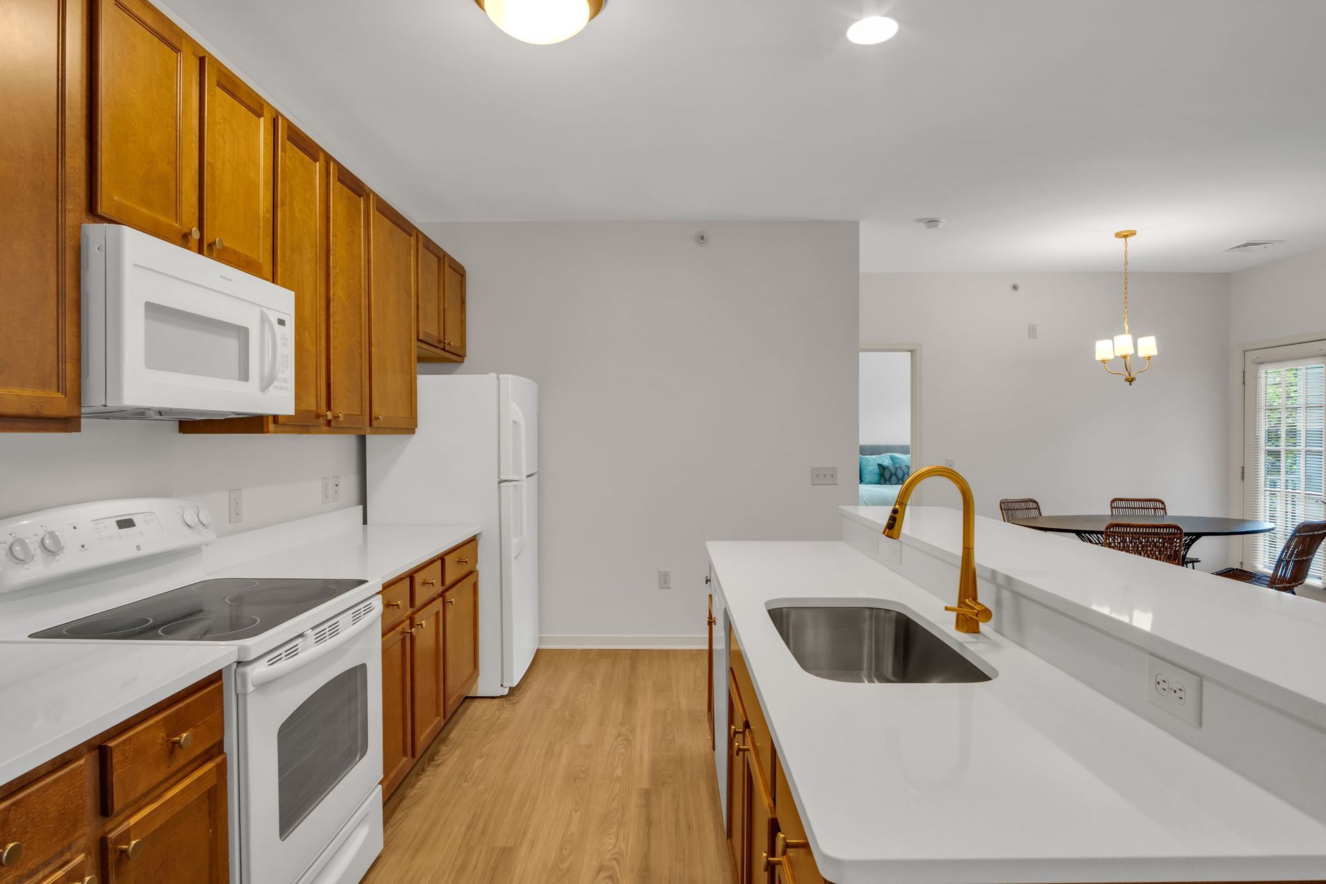 Bright kitchen with white island, wood cabinets, stainless appliances, and hardwood floors