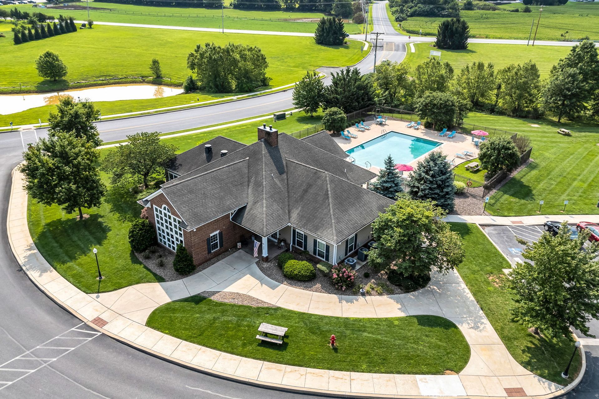 Aerial view of a suburban house with a driveway, lawn, and backyard swimming pool.