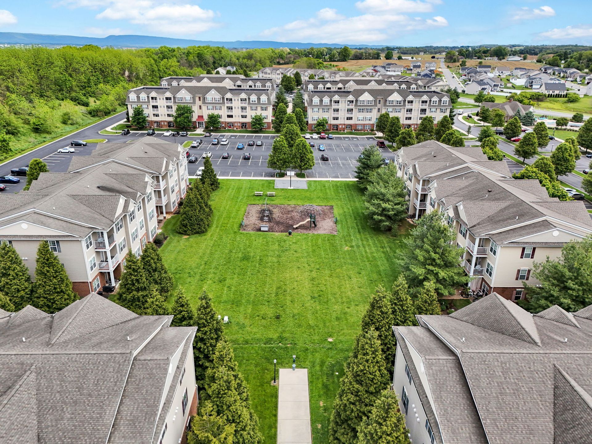 Aerial view of a residential complex with apartment buildings and a green courtyard.