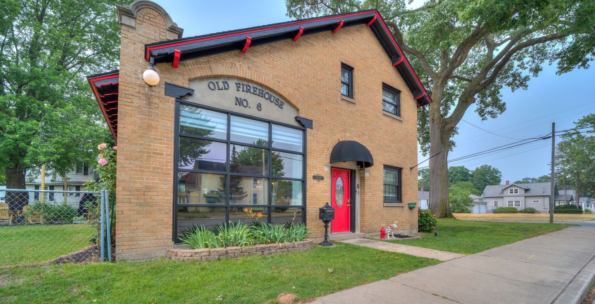 A brick building with a red door and a black awning.