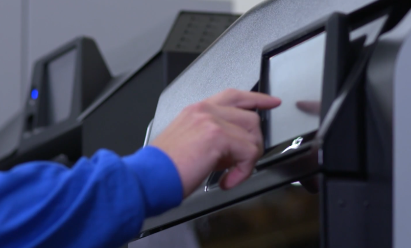 A person in a blue shirt is opening a microwave door.