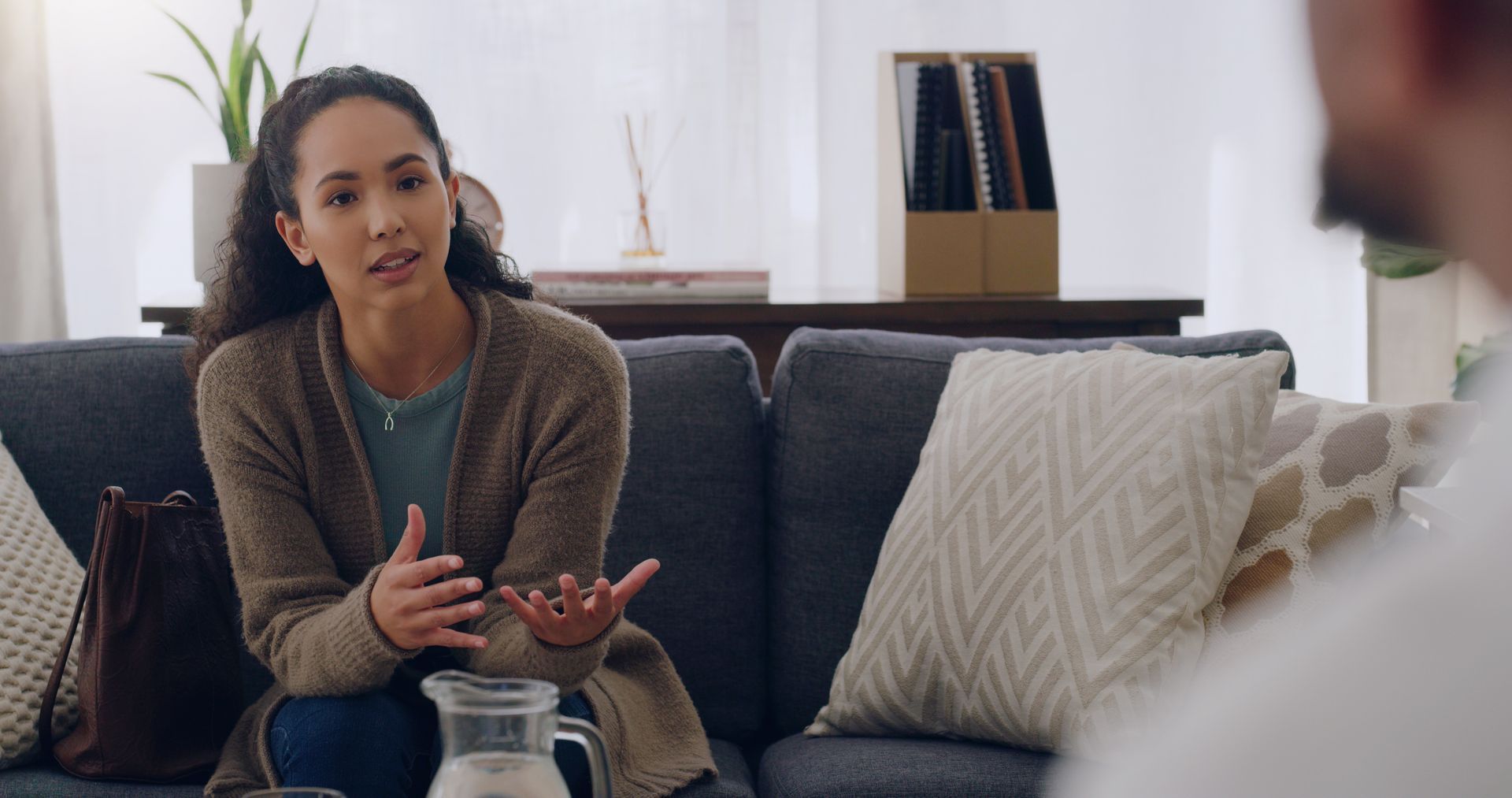 Woman talking with a therapist on a couch during a mental health services session.