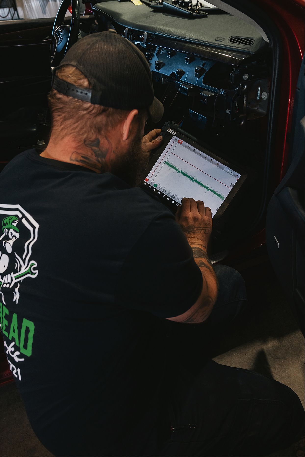 Mechanic uses a tablet to diagnose a vehicle's electrical system inside the car. | Gearhead Autoworks