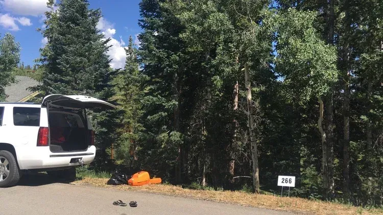 White SUV parked beside a wooded campsite with an orange tent and site marker 206