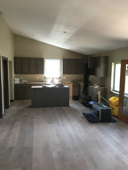 Unfinished kitchen with cabinets, island, window light, and boxes on the floor.