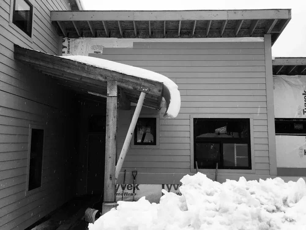 Collapsed awning over a snow-covered entryway on a house exterior